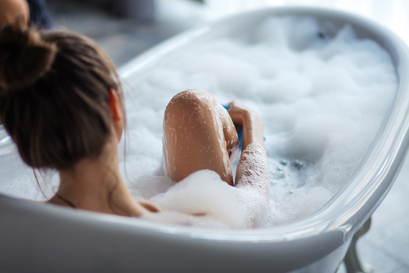 Female,Massaging,Her,Legs,With,Sponge,In,The,Tub.,Back