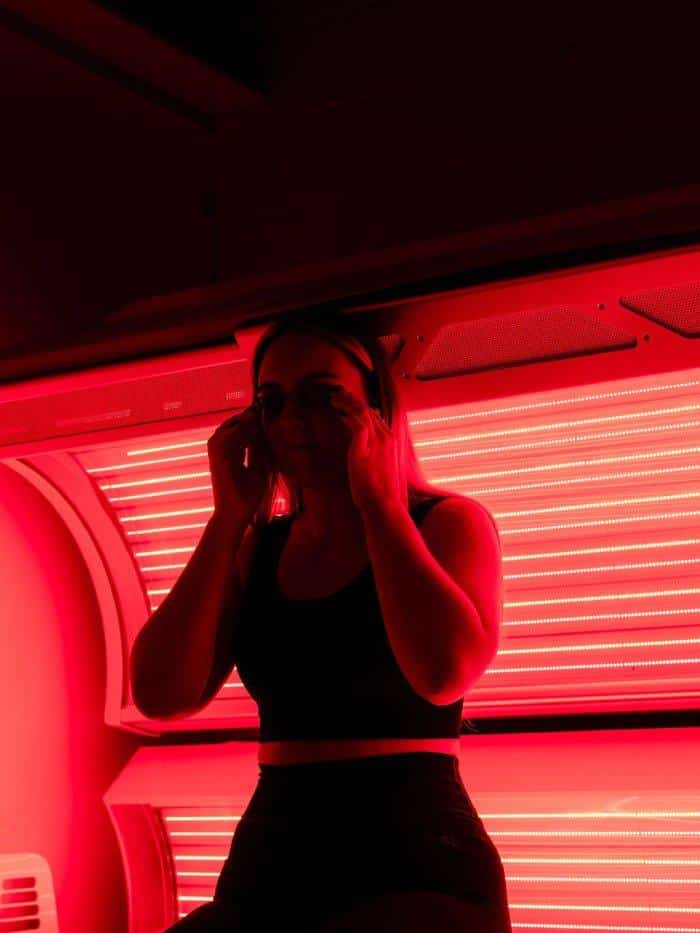 Woman putting on protective eyewear before a full-body red light therapy session at The Tanning Shop UK