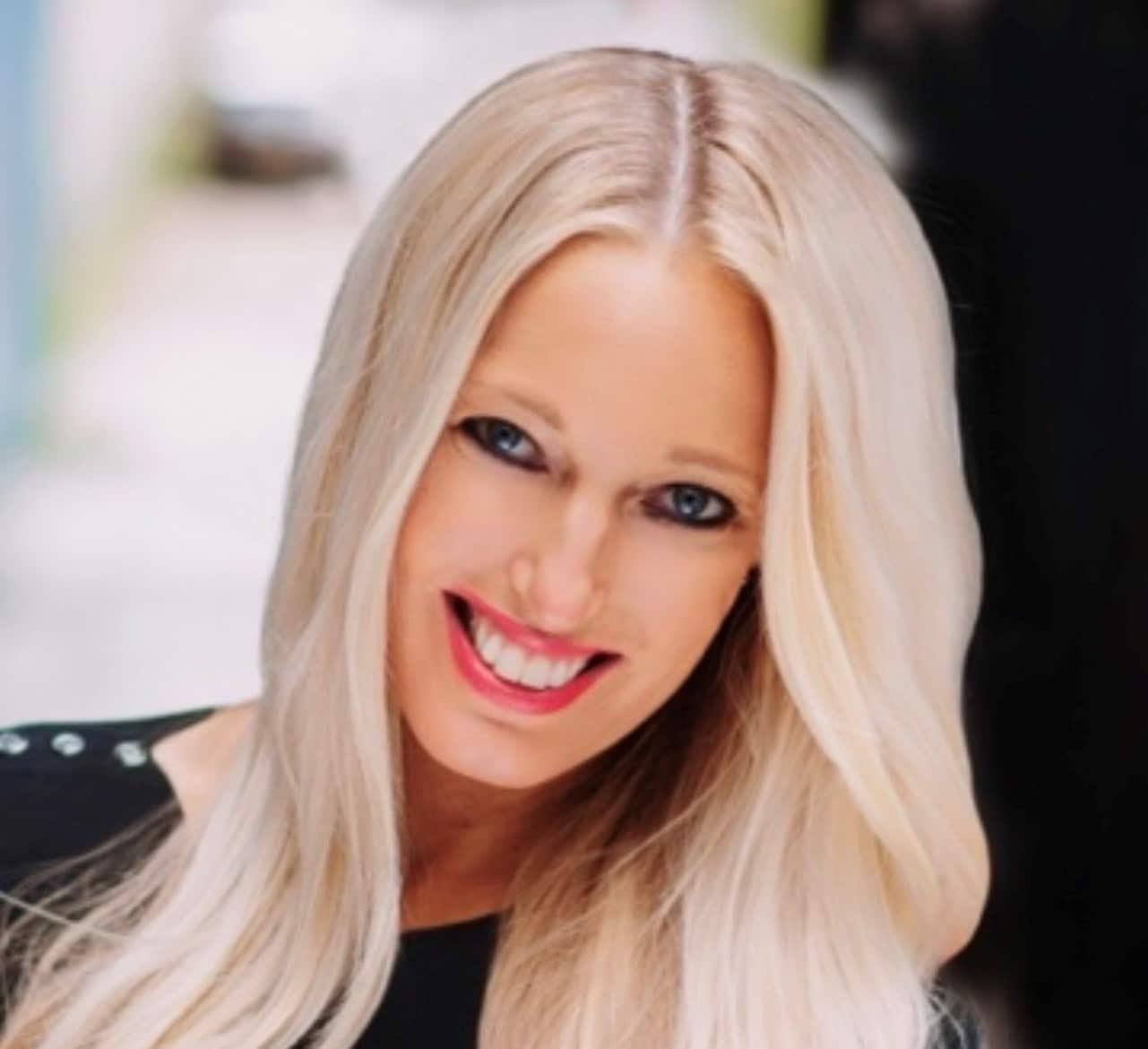 Smiling woman with beautiful glowing tanned skin and blonde hair at The Tanning Shop UK