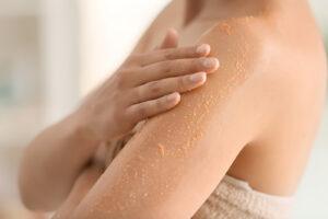 How to prepare for a spray tan - woman exfoliating skin before spray tanning at The Tanning Shop UK
