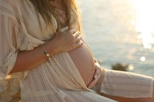 Sunbeds and spray tanning during pregnancy safety guide - pregnant woman at the beach at sunset