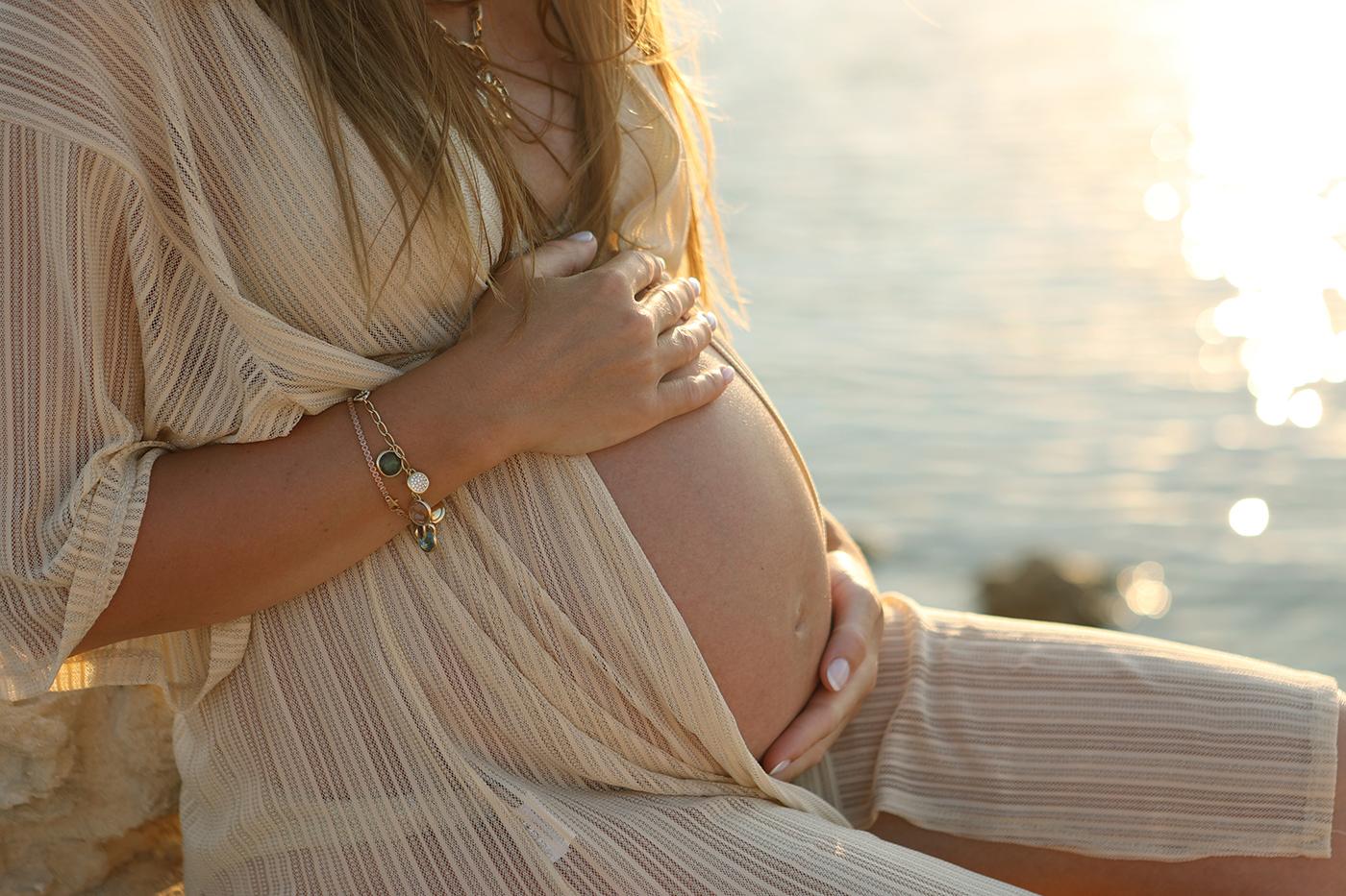 Sunbeds and spray tanning during pregnancy safety guide - pregnant woman at the beach at sunset