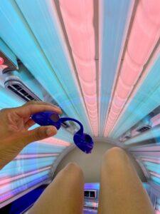 Importance of eye protection on sunbeds - person holding protective UV goggles inside a sunbed at The Tanning Shop UK