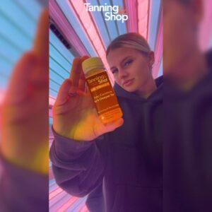 Customer holding Tanning Shot product inside tanning bed at The Tanning Shop Cheltenham
