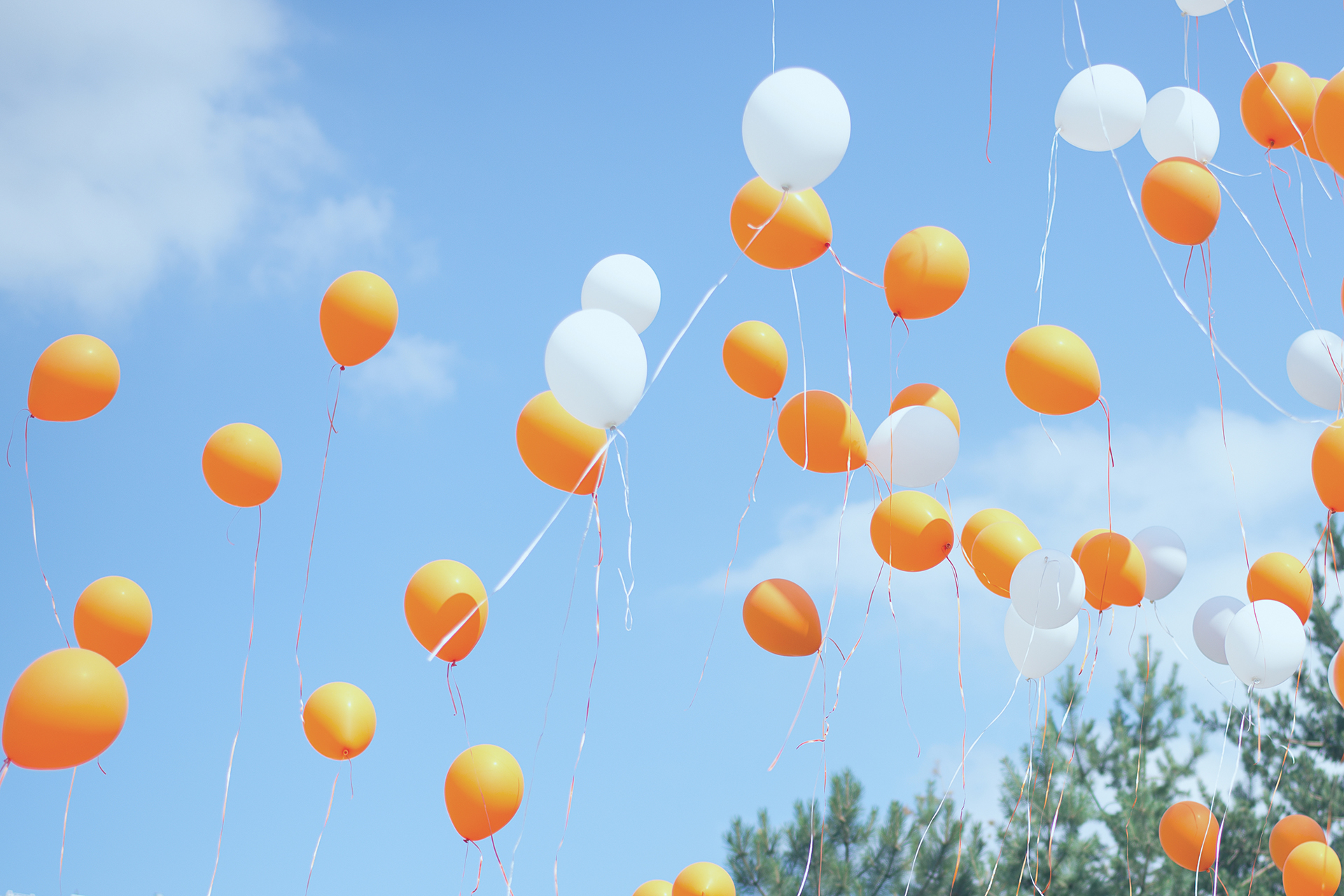 Orange and white balloons floating in a blue sky, celebrating The Tanning Shop UK birthday discount offer
