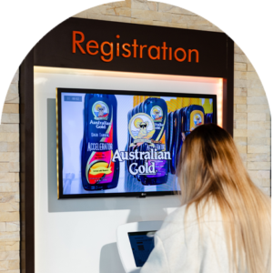 Customer registering at a self-service kiosk with Australian Gold tanning products on screen at The Tanning Shop UK