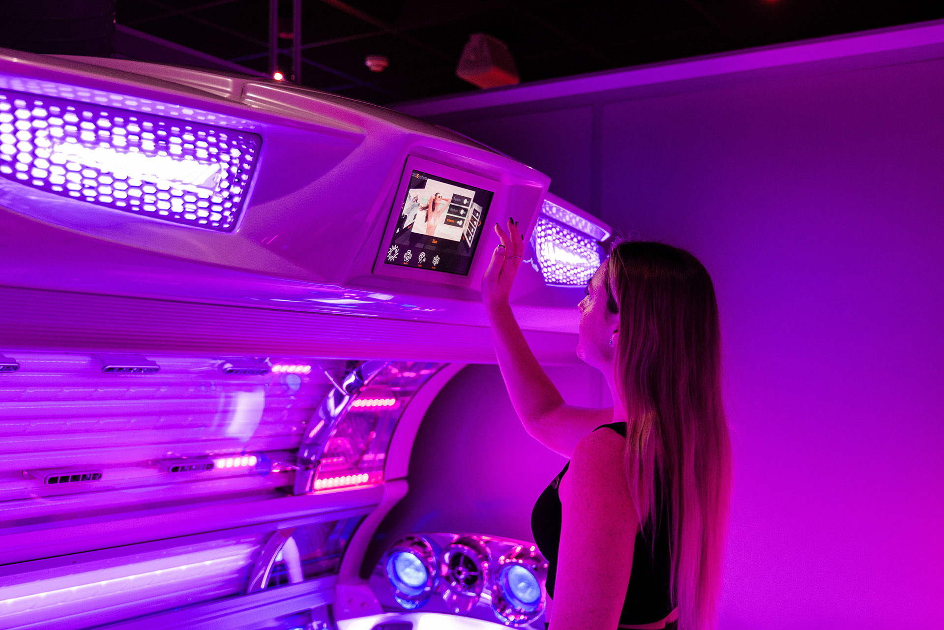 Tanning Shop Sunbed Touchscreen Controls Salon Locator Woman operating the touchscreen control panel on a professional UV sunbed at a Tanning Shop UK salon